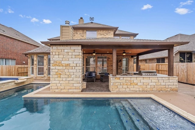 view of swimming pool featuring ceiling fan, a fenced backyard, a fenced in pool, and exterior kitchen