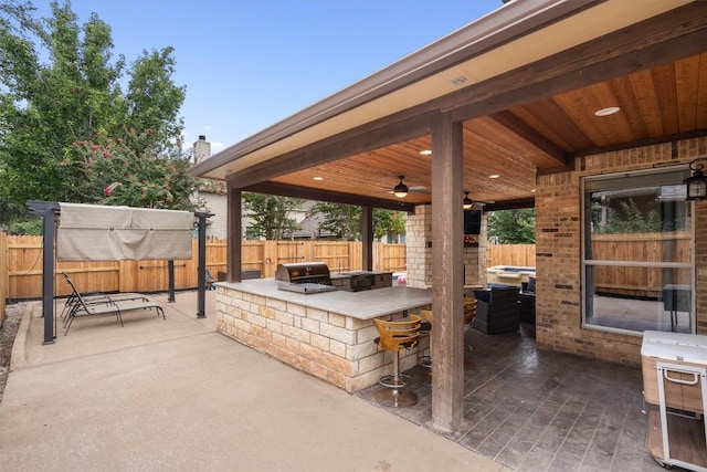 view of patio featuring grilling area, exterior kitchen, a ceiling fan, and fence