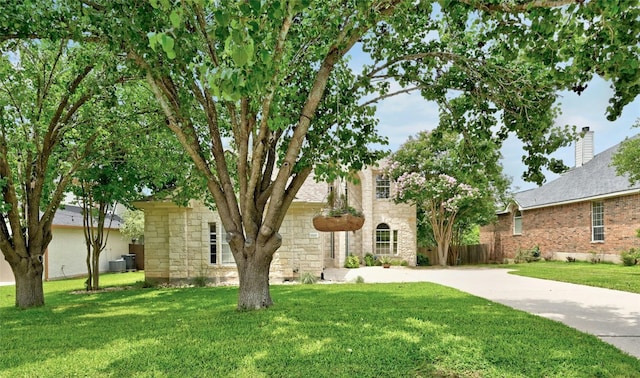 view of front of property with a front lawn and central air condition unit