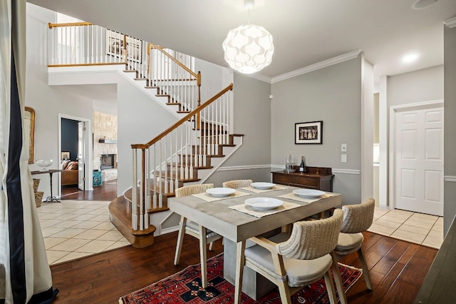 dining area with hardwood / wood-style flooring, a stone fireplace, and crown molding