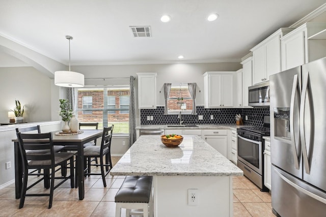 kitchen with sink, white cabinetry, hanging light fixtures, a kitchen island, and stainless steel appliances