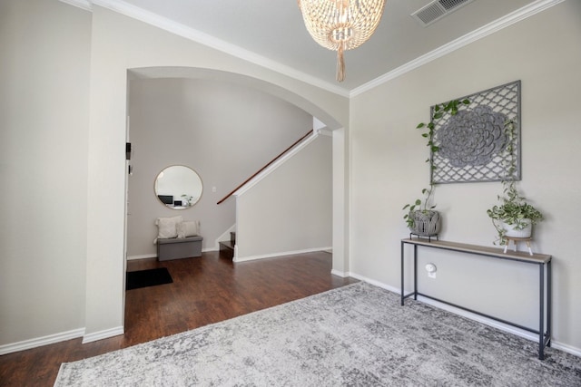 foyer entrance with dark hardwood / wood-style flooring, a notable chandelier, and ornamental molding