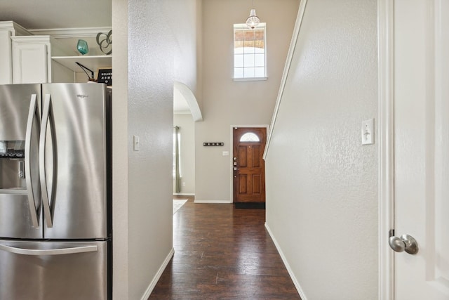 kitchen featuring a towering ceiling, pendant lighting, white cabinets, stainless steel refrigerator with ice dispenser, and dark wood-type flooring