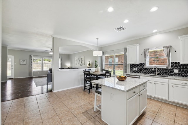 kitchen featuring white cabinetry, a kitchen island, sink, and pendant lighting