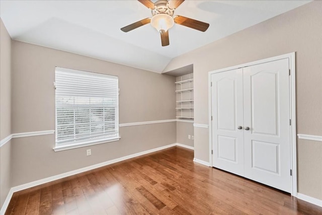 unfurnished bedroom featuring wood-type flooring, a closet, ceiling fan, and vaulted ceiling