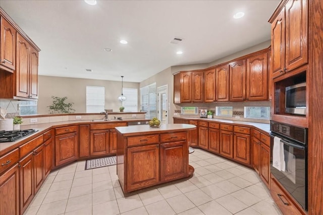 kitchen with pendant lighting, sink, light tile patterned floors, stainless steel appliances, and a center island