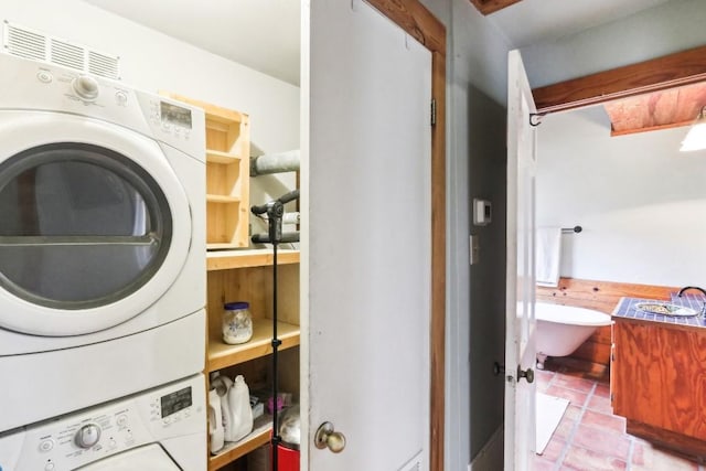 laundry area featuring light tile patterned floors and stacked washer and clothes dryer