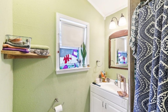 bathroom featuring ornamental molding, vanity, and vaulted ceiling