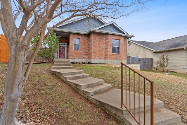 view of front facade featuring brick siding, a front lawn, and fence