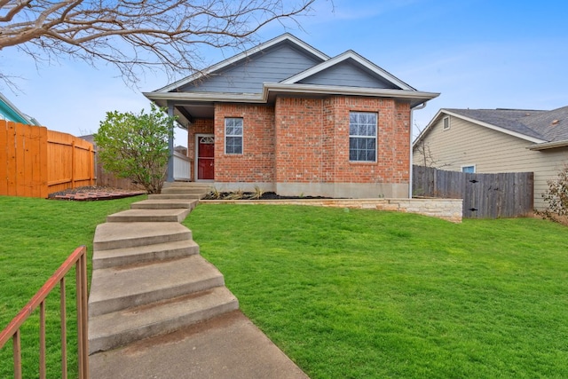 view of front facade with brick siding, a fenced backyard, and a front lawn