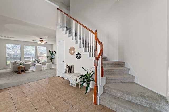 stairs with tile patterned flooring, a towering ceiling, and ceiling fan