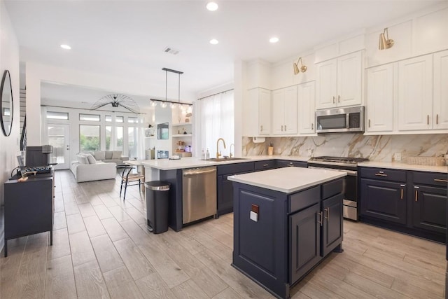 kitchen featuring sink, a center island, hanging light fixtures, appliances with stainless steel finishes, and white cabinets