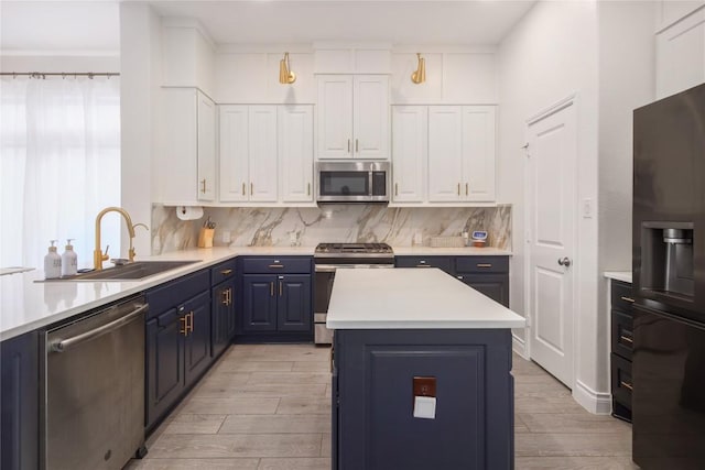 kitchen featuring blue cabinetry, sink, appliances with stainless steel finishes, decorative backsplash, and white cabinets