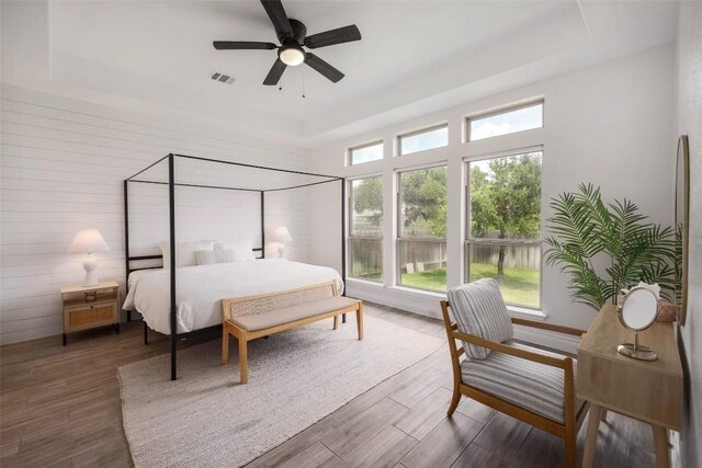 bedroom featuring ceiling fan, dark hardwood / wood-style flooring, and a raised ceiling