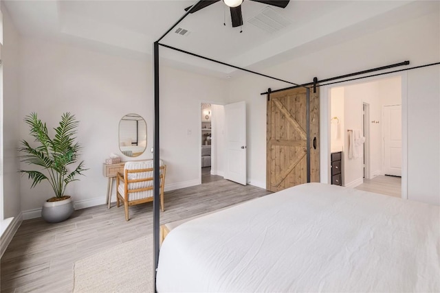 bedroom featuring hardwood / wood-style flooring, a barn door, and ceiling fan