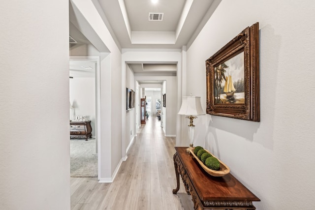 hall featuring a raised ceiling and light hardwood / wood-style floors