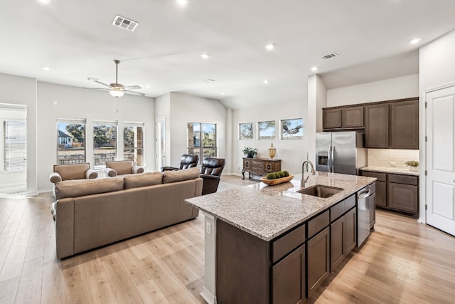 kitchen featuring sink, dark brown cabinetry, stainless steel appliances, a center island with sink, and light wood-type flooring