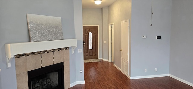 entrance foyer featuring a high ceiling, a tile fireplace, and dark hardwood / wood-style flooring