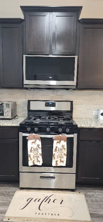 kitchen with a toaster, stainless steel appliances, light stone countertops, backsplash, and wood finished floors