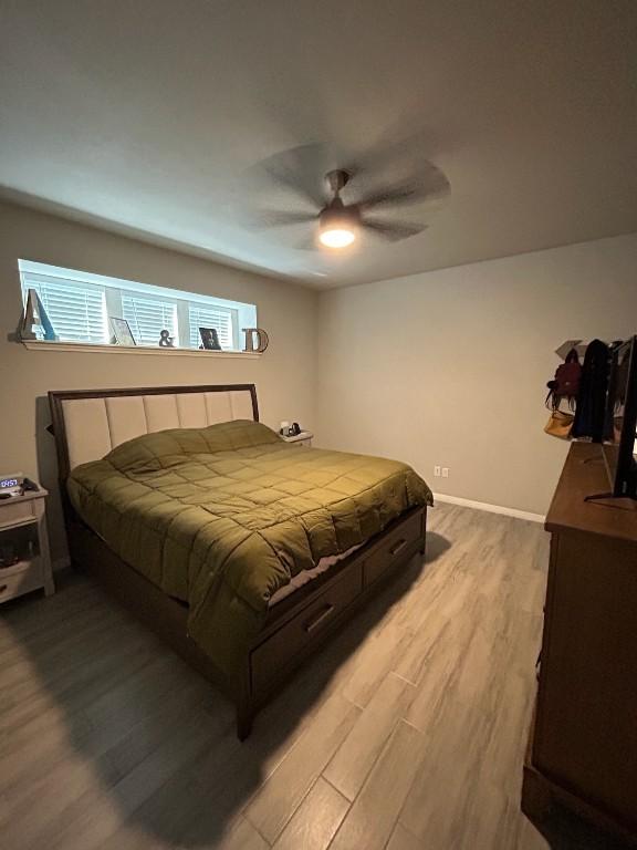 bedroom featuring light wood-style flooring, baseboards, and ceiling fan