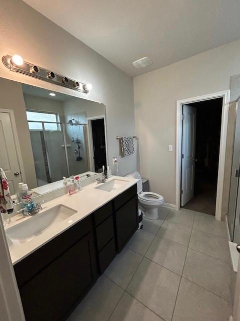 bathroom featuring tile patterned flooring, vanity, an enclosed shower, and toilet