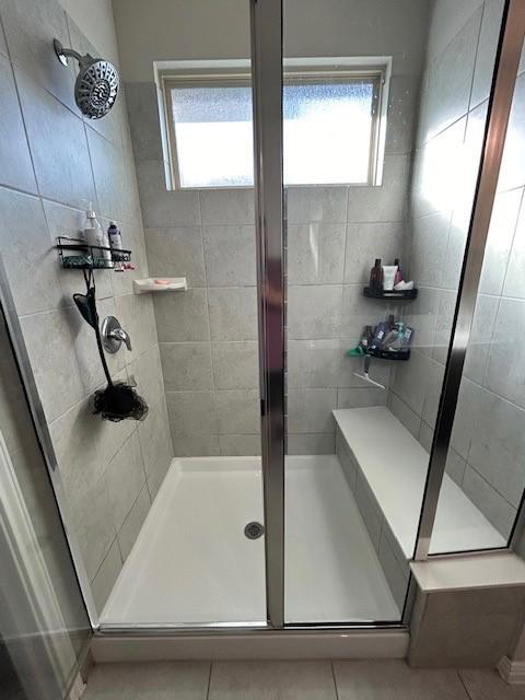 bathroom with a stall shower and tile patterned flooring