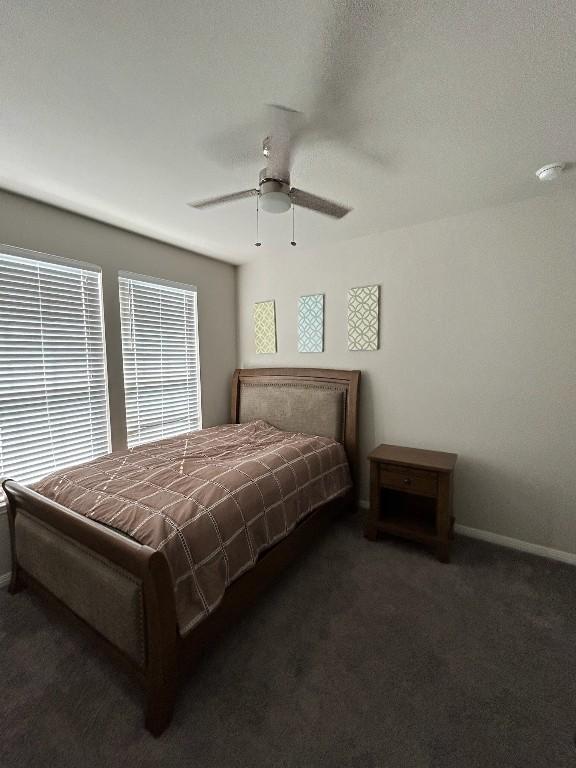 bedroom with dark carpet, a ceiling fan, and baseboards