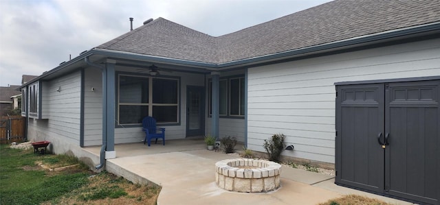 back of property with an outdoor fire pit, a ceiling fan, a shingled roof, and a patio