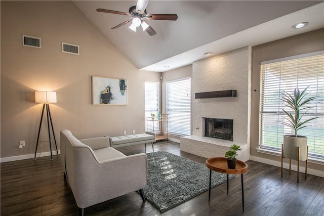 living room with a brick fireplace, dark wood-type flooring, high vaulted ceiling, and ceiling fan