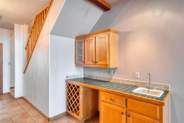 kitchen featuring lofted ceiling with beams, sink, tile counters, and light tile patterned floors