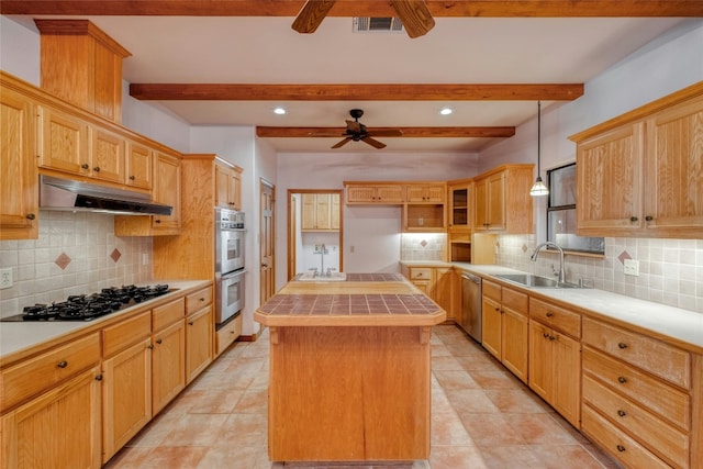 kitchen featuring appliances with stainless steel finishes, tile countertops, pendant lighting, sink, and a center island