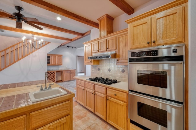 kitchen with sink, gas cooktop, tile counters, double oven, and backsplash