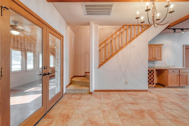 entryway with sink, light tile patterned floors, a chandelier, and french doors