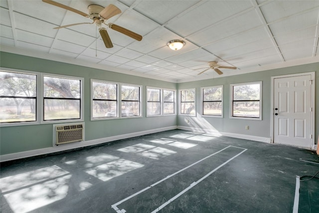 unfurnished sunroom with ceiling fan, a paneled ceiling, and a wall mounted AC