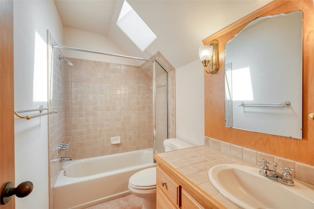 full bathroom with tiled shower / bath, vanity, toilet, and vaulted ceiling