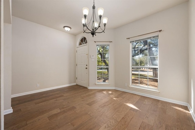 unfurnished dining area featuring wood-type flooring and a chandelier