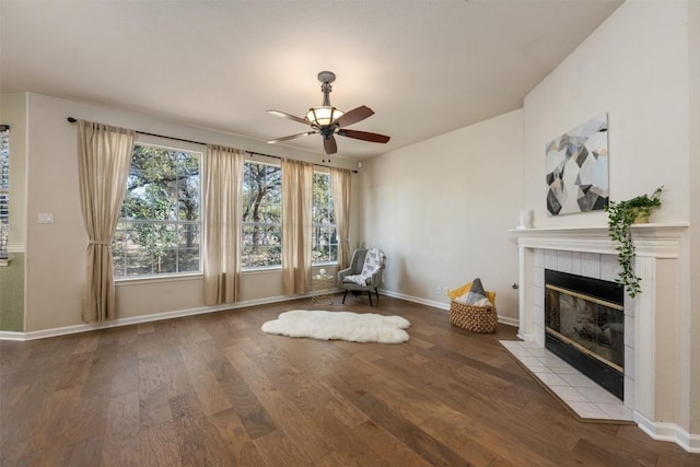 unfurnished room with hardwood / wood-style flooring, a tile fireplace, and ceiling fan