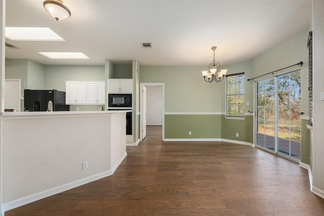 kitchen with pendant lighting, a skylight, white cabinetry, dark hardwood / wood-style flooring, and black appliances