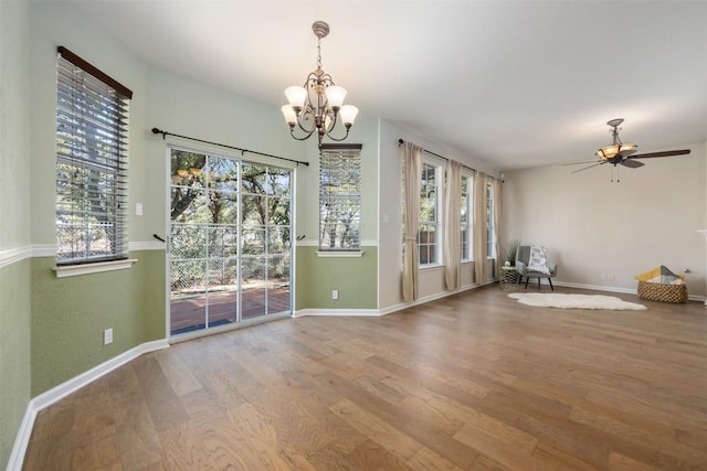 interior space featuring wood-type flooring, a healthy amount of sunlight, and ceiling fan with notable chandelier