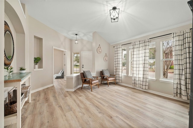 living area with lofted ceiling, a wealth of natural light, and light hardwood / wood-style flooring