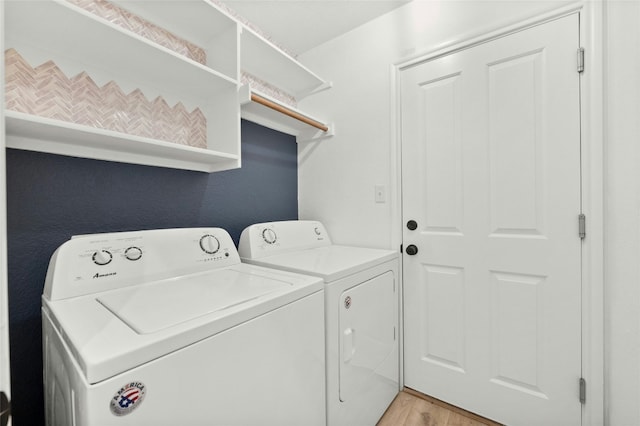 laundry room with washing machine and clothes dryer and light hardwood / wood-style floors