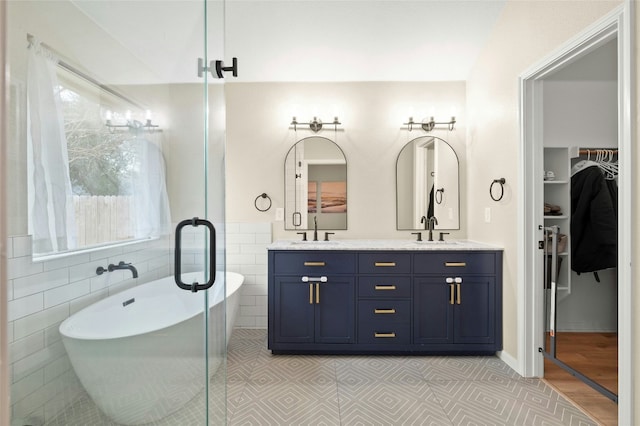 bathroom featuring tile walls, a bath, vanity, and tile patterned flooring