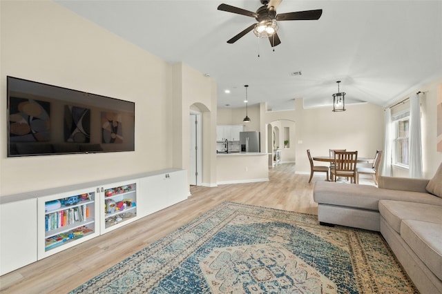 living room featuring vaulted ceiling, sink, ceiling fan, and light hardwood / wood-style floors