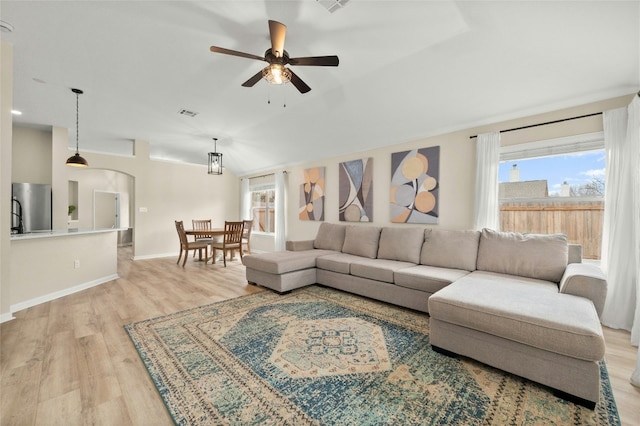 living room featuring ceiling fan, plenty of natural light, lofted ceiling, and light wood-type flooring