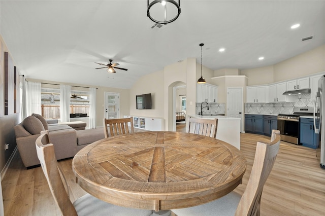 dining room featuring ceiling fan, vaulted ceiling, sink, and light hardwood / wood-style floors