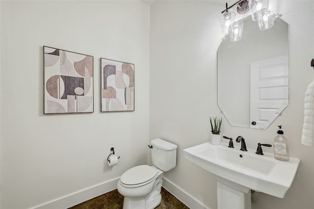 half bathroom with baseboards, a sink, and toilet