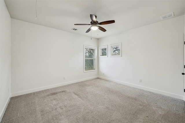 carpeted spare room with baseboards, visible vents, and ceiling fan