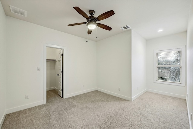 unfurnished bedroom with visible vents, a walk in closet, and light colored carpet