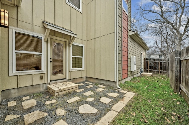 property entrance featuring board and batten siding, a patio area, and fence