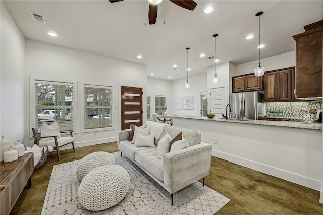 living room with ceiling fan, sink, and a healthy amount of sunlight